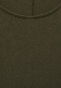 Tessuto a coste di un verde oliva scuro con una texture liscia, caratterizzato da un colletto rotondo e dettagli di cucitura visibili.