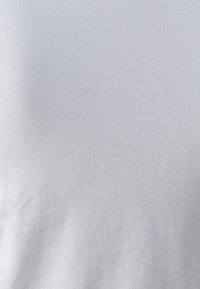 Lys grå stoftekstur med subtile vertikale og diagonale folder, der viser fine væve detaljer.