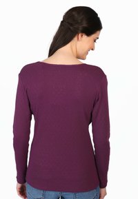 Lila Langarmshirt mit rundem Ausschnitt, strukturiertem Punktmuster und bequemer Passform, kombiniert mit Jeans.