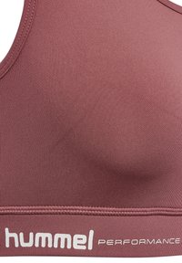 Bordowy stanik sportowy wykonany z gładkiego, elastycznego materiału, z okrągłym dekoltem i pasem z białym logo "hummel PERFORMANCE".