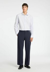 Camicia button-up a righe blu chiaro e bianco con maniche lunghe, abbinata a pantaloni eleganti blu scuro e scarpe nere.