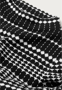 Mustavalkoinen neulottu kangas, jossa on keskenään liitoksissa olevia geometrisia kuvioita, sisältäen sekä täysiä että ääriviivoilla varustettuja muotoja pehmeässä tekstuurissa.