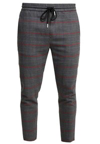 Pantaloni della tuta a quadri neri e grigi con dettagli rossi, vita elasticizzata e coulisse regolabile. Design con gambe affusolate e texture liscia.