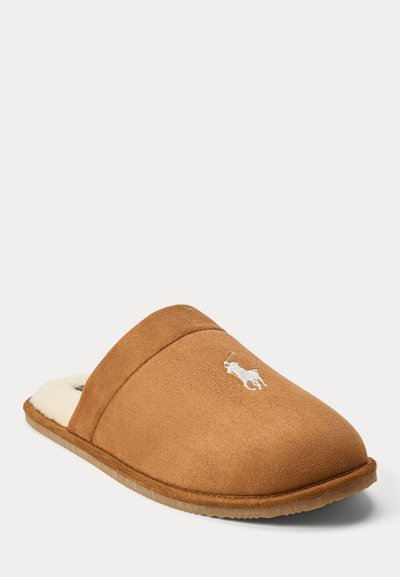 Chinelo de camurça castanha com forro macio creme, bico arredondado e detalhe de logótipo bordado. Sola leve com acabamento texturizado.