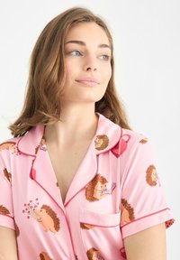 Camisón rosa con un patrón de erizos, mangas cortas y cuello con ribete rojo en contraste. Tejido suave con ilustraciones divertidas.