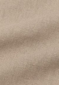 Tessuto intrecciato di un beige chiaro con una superficie testurizzata, che presenta una tessitura uniforme e compatta e linee diagonali sottili.