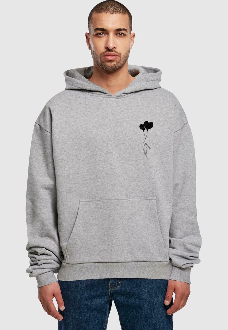Grauer Baumwoll-Hoodie mit einer Fronttasche, auf der Brust mit einer schwarzen Grafik einer Figur, die zwei schwarze Ballons hält. Lässiger Schnitt, Kapuze mit Kordelzug.