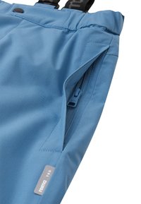 Pantaloni din țesătură ușoară, de culoare albastră, cu bretele ajustabile, având o buzunar cu fermoar și un etichetă cu logo-ul "reima TEC". Textură netedă.