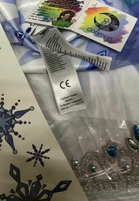 Costume fabric in pastel blue with a satin finish, wrapped alongside a silver jeweled tiara and care label. Includes colorful product tags.