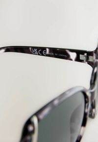 Occhiali da sole con una montatura scura caratterizzata da un motivo marmorizzato. Include un logo visibile sul braccio, che riporta la dicitura "CE" e "MADE IN CHINA."