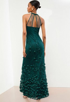 Rochie de seară verde închis cu un corset ajustat și o fustă fluidă împodobită cu aplicații în formă de frunză, având un decolteu tip halter.
