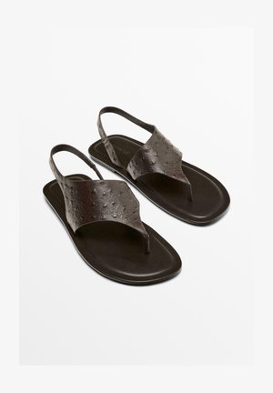 Mørkebrune læder thong-sandaler med teksturerede stropper og slingback-design på flade såler, vist side om side på hvid baggrund.