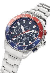 Reloj de acero inoxidable con un bisel azul y rojo, esfera navy, marcadores de hora blancos, tres subesferas y una correa de acero plata. Modelo: Nautica.