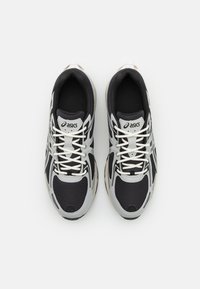 Black and gray athletic shoes with a mesh upper, textured accents, and a cushioned sole. Features white laces and brand logo on the tongue.