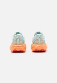 Une paire de chaussures de sport avec un dessus en maille respirante bleu clair et une semelle orange texturée, présentant une forme arrondie et des crampons de traction bien visibles.