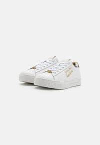 Hvite sneakers med glatt skinnfinish, gullakenter og strukturert gummisåle med "JEANS COUTURE" preget på siden.