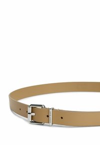 Ceinture synthétique beige à texture lisse, dotée d'une boucle en métal argenté et d'une plaque gravée "Tommy Jeans". Ajustable avec des trous.