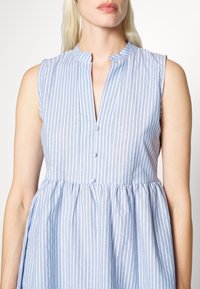 Robe sans manches rayée bleue et blanche, dotée d'un col mandarin, d'une patte de boutonnage et d'une taille froncée pour une silhouette de jupe évasée.