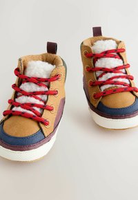 Braune und blaue Kleinkindstiefel mit roten Schnürsenkeln, Futter aus Kunstpelz, strukturiertem Wildleder-Obermaterial und Gummisohlen, mit einer Zuglasche an der Ferse.