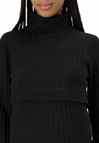 Maglione nero a coste con collo alto, dal design cropped, con una trama fine e maniche lunghe, che offre una vestibilità accogliente.