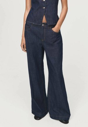 Mørkeblå denim brede bukser har høj talje, fem lomme design og kontrasterende orange syninger. Stoffet ser holdbart ud, men er samtidig blødt.