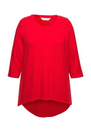 Červený top s krátkým rukávem vyrobený z měkké tkaniny, s kulatým výstřihem a asymetrickým lemem, který je vzadu delší.