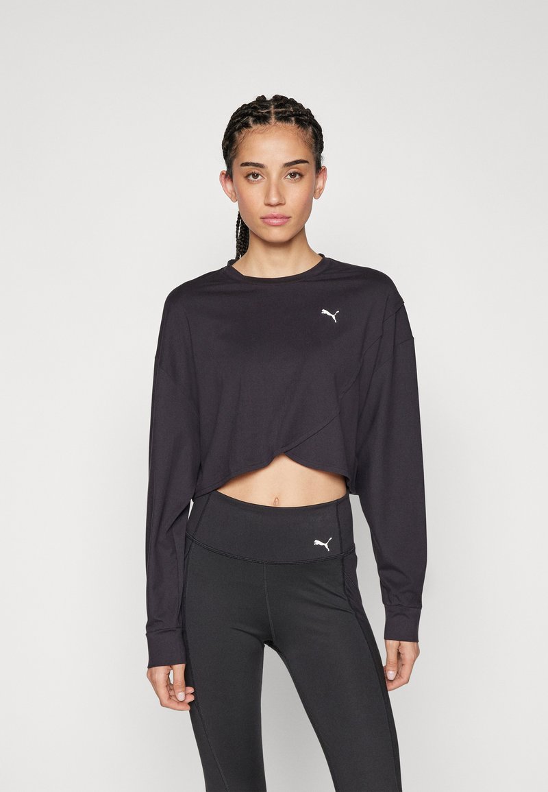 Schwarzes, kurzes langärmliges Oberteil mit runder Halslinie und einem weißen Puma-Logo, kombiniert mit hoch taillierten schwarzen Leggings, die ebenfalls ein Logo tragen.