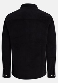 Camisa de pana negra con collar, mangas largas y puños con botones. Presenta una textura de estrías verticales y botones sutiles en blanco.