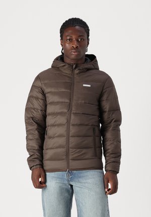Brown puffer jacket with a hood, featuring horizontal quilted design, front zipper, and side pockets. Worn over a black top and blue jeans.