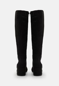 Bottes cuissardes en daim noir avec un talon bloc, dotées d'une texture lisse et d'une fermeture éclair à l'arrière. Design simple et élégant.