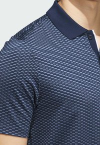Navy blue polo shirt with a textured geometric pattern, featuring a solid collar and two-button placket. Soft, stretchy fabric.