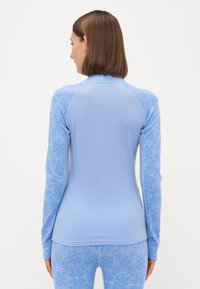 Ανοιχτό μπλε τοπ με μακριά μανίκια και ριμπ υφή, που διαθέτει μοτίβο στα μανίκια και λείο κορμό. Κολλητό και άνετο.