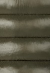 Giacca puffer verde oliva in tessuto con una texture liscia e lucida, caratterizzata da sezioni a righe orizzontali imbottite e dettagli di cucitura visibili.