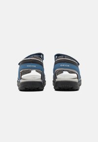 Sandalias GEox en azul y gris con diseño de espalda abierta, suela de goma, correas ajustables y acentos de malla transpirable.