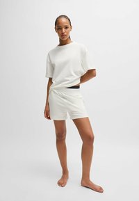 Vitt t-shirt i kortärmad design och matchande shorts, tillverkade av mjukt material, med en avslappnad passform och subtil logotypdetalj på bröstet.