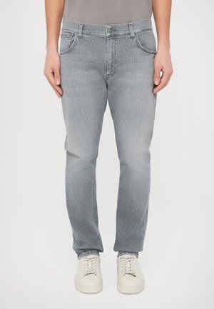 Ανοιχτό γκρι τζιν από τζιν ύφασμα, με κλασικό σχέδιο πέντε τσεπών και ίσια μπατζάκια. Συνδυάζονται με λευκά αθλητικά παπούτσια.