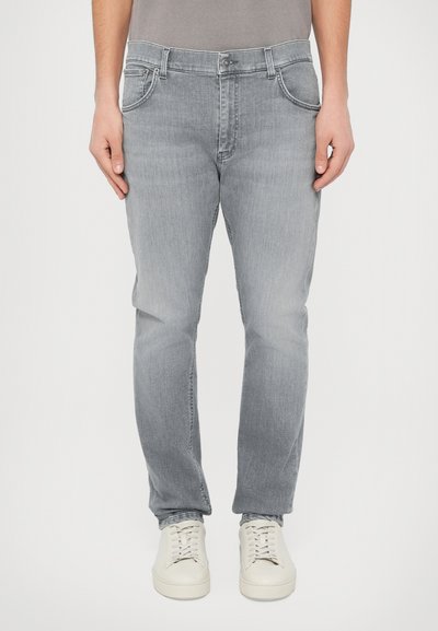 Jean gris clair en denim, avec un design classique à cinq poches et des jambes droites. Complété par des baskets blanches.