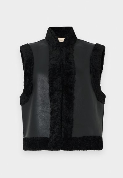 Gilet noir présentant une combinaison de cuir et de texture duveteuse, avec un col haut et sans manches, mettant en avant un panneau avant contrastant.