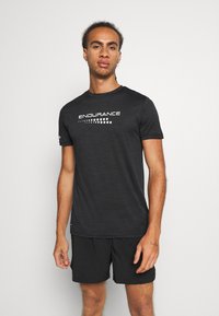 Czarny sportowy t-shirt z krótkim rękawem i okrągłym dekoltem, z napisem "ENDURANCE" w białym kolorze na klatce piersiowej.