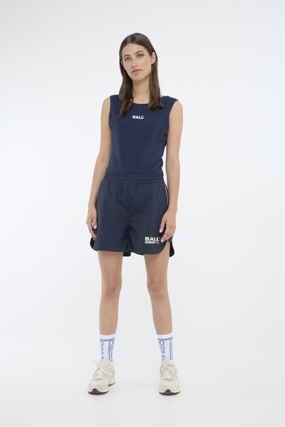 Marineblå tank topp med "BALL" logo, kombinert med matchende shorts med logo og sidestriper. Hvite sokker med blå geometrisk mønster, beige sneakers.