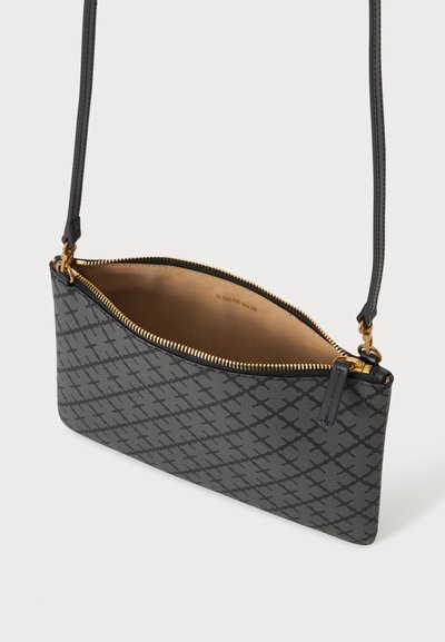 Petit sac bandoulière gris avec motif noir, fermeture éclair dorée et sangle fine réglable, présenté ouvert avec doublure intérieure beige.