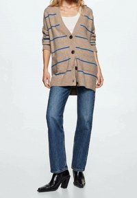 Brązowy sweter na guziki z niebieskimi paskami, z przodu zapinany na guziki i z prążkowanymi mankietami. W połączeniu z niebieskimi, prostymi spodniami jeansowymi i czarnymi botkami na obcasie.