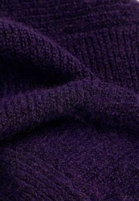 Tela de punto en color púrpura intenso, que muestra una textura suave con acanaladuras prominentes y un acabado peludo. Presenta variaciones sutiles en el tono.