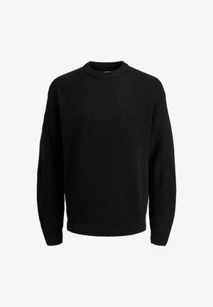 Kurtka puchowa w miękkim szarym kolorze z wysokim kołnierzem, noszona na czarnej dzianinowej bluzie; zestawiona z oliwkowymi spodniami w szerokim kroju i szarymi trampkami.