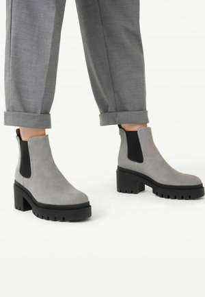 Botas de tobillo de ante gris con paneles laterales elásticos negros y suelas de goma negra gruesas. Presenta una punta redonda y un tacón apilado para mayor estabilidad.