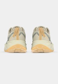 Μπεζ αθλητικά παπούτσια με υφασμένο επάνω μέρος, γκρι λεπτομέρειες, πορτοκαλί κορδόνια και πάτο παχύ και μαλακό. Η πίσω όψη δείχνει εμφανές τμήμα έλξης και πέλμα με μοτίβο.