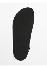 Black sandal with a smooth, flat rubber sole. Features a rounded shape and minimal detailing. The texture appears slightly matte.