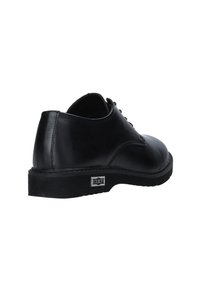 Scarpa in pelle nera con punta arrotondata, texture liscia, design con lacci e suola in gomma con motivo. Presenta un accento con logo sul tallone.