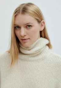 Ecrufarbener Rollkragenpullover mit einem strukturierten Rippmuster, ausgestattet mit einem umgeschlagenen Kragen und weichem, gestricktem Stoff.