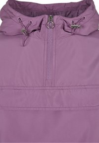 Violetti huppari, jossa on etuvetoketju ja säädettävät narut, joissa on metalliset tukkikappaleet.